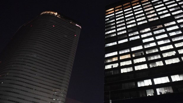 長時間労働による社員の自殺を受け、午後10時に一斉消灯されるようになった電通の本社ビル(左)=2016年10月24日、猪飼健史撮影
