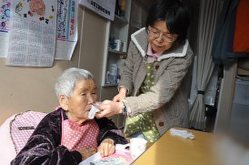 鎌田文子さん(右)は手狭な仮設住宅で義母マサさんを介護する=福島県南相馬市で2015年2月