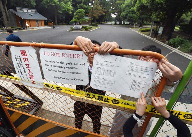 園内立ち入り禁止の張り紙をして代々木公園の門を閉鎖する関係者たち=東京都渋谷区で2014年9月4日午後3時10分、竹内紀臣撮影