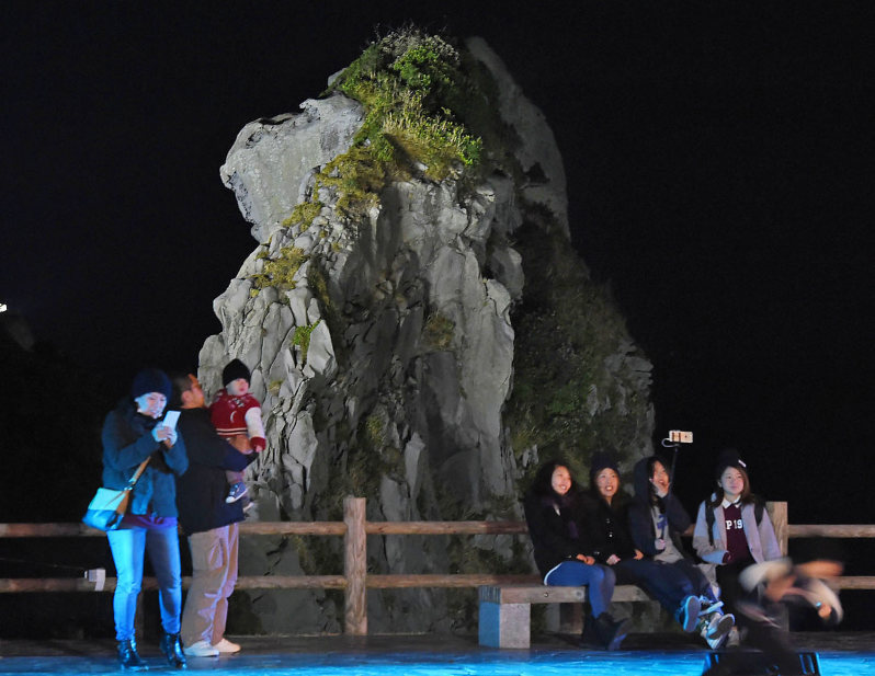 ライトアップされた猿岩(奥)。手前は記念写真を撮る人たち=長崎県壱岐市で2015年12月31日午後6時12分、矢頭智剛撮影