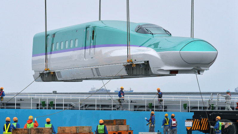 輸送船からクレーンで陸揚げされる北海道新幹線の先頭車両=函館港で2014年10月、手塚耕一郎撮影