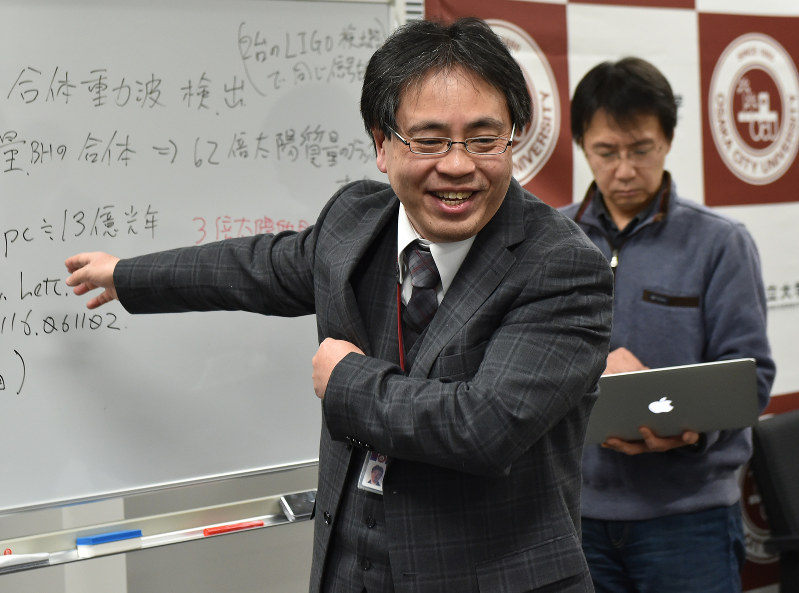 重力波初観測の発表を受け、内容を説明する大阪市立大学大学院理学研究科の神田展行教授(手前)。奥は田越秀行准教授=大阪市住吉区で2016年2月12日午前1時4分、三浦博之撮影