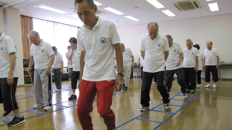 声を出して数を数えるのと同時に、マス目を使ってステップを踏みながら進む参加者=愛知県大府市で細川貴代撮影