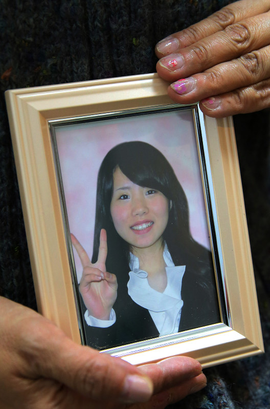 花岡磨由さんの遺影を持つ母。爪には磨由さんが描いたネイルアートが残る=東京都千代田区で2016年2月4日、長谷川直亮撮影