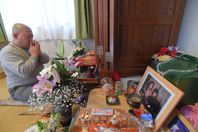骨つぼ(右端)がひとつだけ置かれた部屋で仏壇に手を合わせる小松則明さん=岩手県大槌町で2016年3月11日午前9時、和田大典撮影