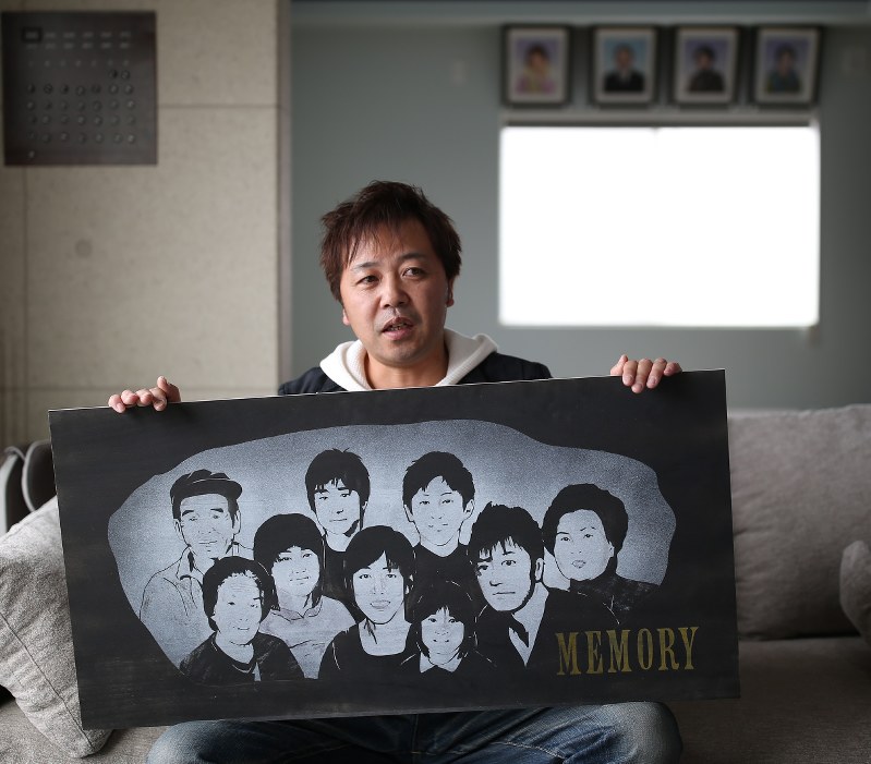 再建した自宅リビングで家族の肖像画を手にする岩崎満さん=福島県相馬市で、小出洋平撮影