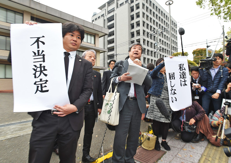 仮処分申請の抗告審で差し止めが認められず、「不当決定」「私達は屈しない」の垂れ幕を掲げる弁護士ら=宮崎市で2016年4月6日午前10時37分、矢頭智剛撮影