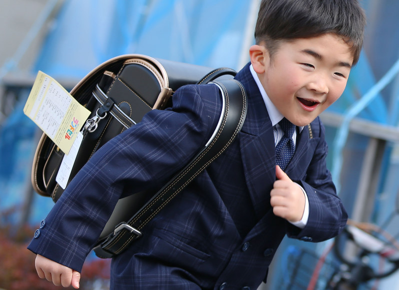 今春の小学校入学を控え、新しいランドセルを背負って仮設住宅前を走り回る藤原昂平君。「スーツも着る!」と撮影の前には、入学式で着るスーツ姿で登場=岩手県陸前高田市で2016年2月27日、小川昌宏撮影