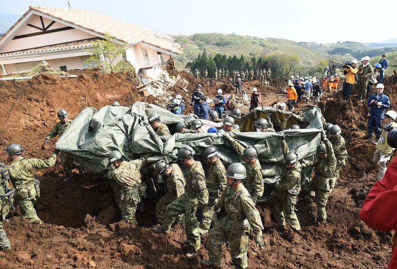 土砂の中から発見した行方不明者を搬送する自衛隊員ら。重機と手作業で数メートルの深さまで掘り下げて発見した=熊本県南阿蘇村河陽で2016年4月19日午前9時32分、丸山博撮影