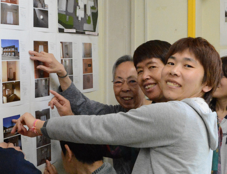 新施設の写真を前に笑顔を見せる利用者たち=群馬県高崎市寺尾町の「のぞみの園」で2016年4月19日、山本有紀撮影