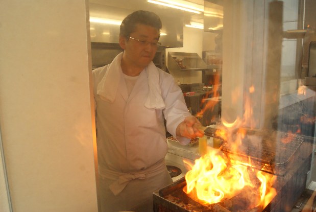 店主の高取宗茂さん。炎を上げて豪快に焼き上げる演出性も売り物