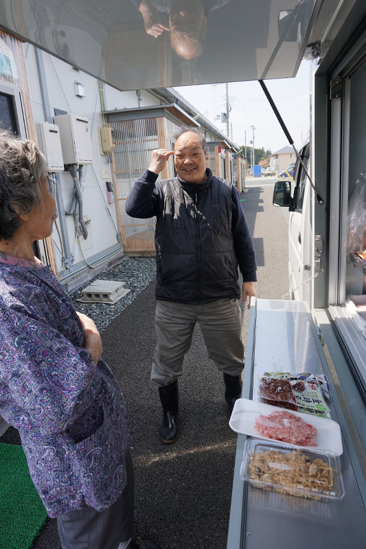 仮設住宅での移動販売でなじみの客と会話する谷地茂一さん=福島県南相馬市鹿島区で