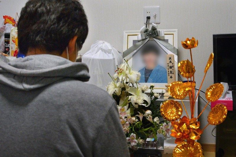 車中泊で亡くなった母恵子さんの遺影の前に座る長男の光彦さん=熊本県氷川町で2016年4月29日、今手麻衣撮影(一部画像を処理しています)