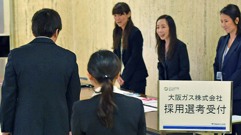 大阪ガスのグループディスカッションに参加するため受付に向かう学生たち(手前)=大阪市中央区で6月1日、川平愛撮影