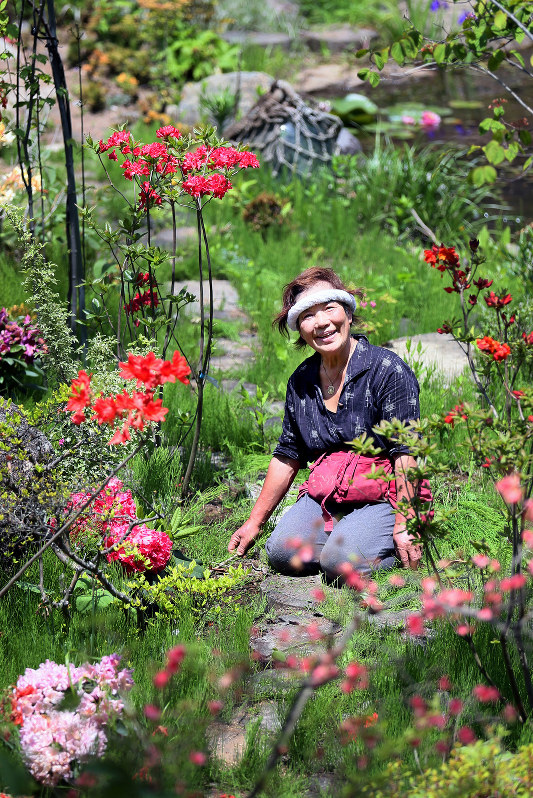 避難先に築き上げた庭園で草花を手入れし、笑顔を見せる遠藤富美さん=福島県田村市で2016年5月、森田剛史撮影