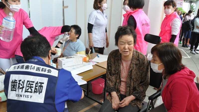 益城町総合体育館前に設けられた歯科コーナーで歯科医師の診察を受ける人たち=熊本県益城町木山で2016年4月28日、中村清雅撮影