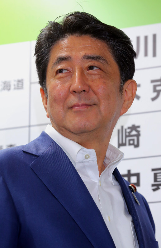 当選確実となった候補者名ボードに花を付け、笑顔を見せる安倍晋三首相=東京都千代田区の自民党本部で2016年7月10日午後9時44分、長谷川直亮撮影