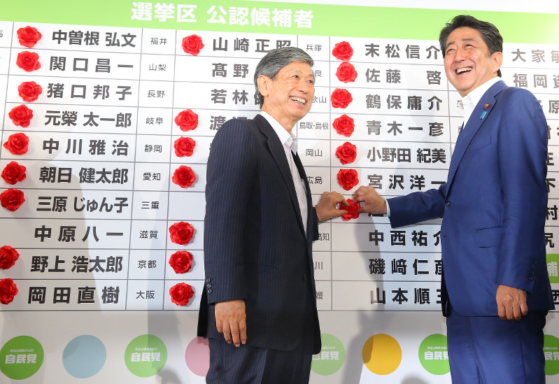 当選確実となった候補者名ボードに花を付け、笑顔を見せる安倍晋三首相(右)と自民党の高村正彦副総裁=東京都千代田区の同党本部で2016年7月10日午後9時47分、長谷川直亮撮影
