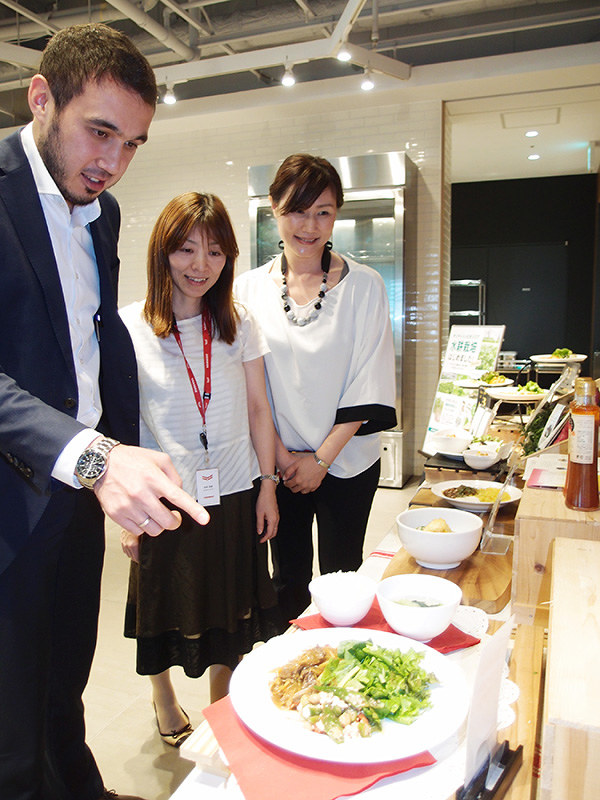 ヤンマーの社員食堂で日本人の同僚と一緒にムスリム向けメニューを選ぶイブラギモブさん(左)=大阪市北区で、土屋渓撮影
