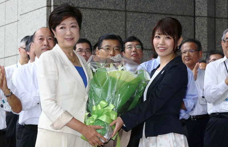 登庁し、花束を贈られて笑顔を見せる小池百合子・新東京都知事(左)=2016年8月2日