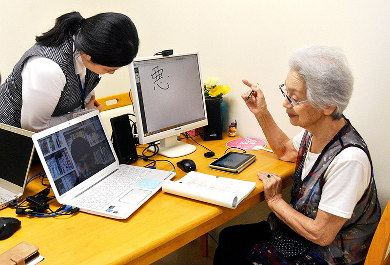 スカイプを使い、離れた場所にいる留学生に漢字の書き順を教える植木節子さん(右)=岡山市北区で、林田奈々撮影