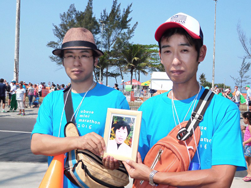 レース会場の沿道から母の遺影を手に声援を送った荒井の長兄英之さん(右)と次兄康徳さん=リオデジャネイロで2016年8月19日、岸達也撮影