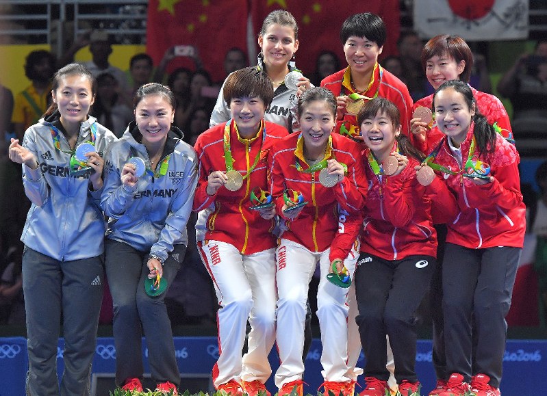 卓球女子団体で銅メダルを獲得し、表彰台で1位の中国、2位のドイツの選手らと記念撮影に応じる(前列右から)伊藤美誠、福原愛と石川佳純(後列右端)=リオデジャネイロのリオ中央体育館で16日、和田大典撮影
