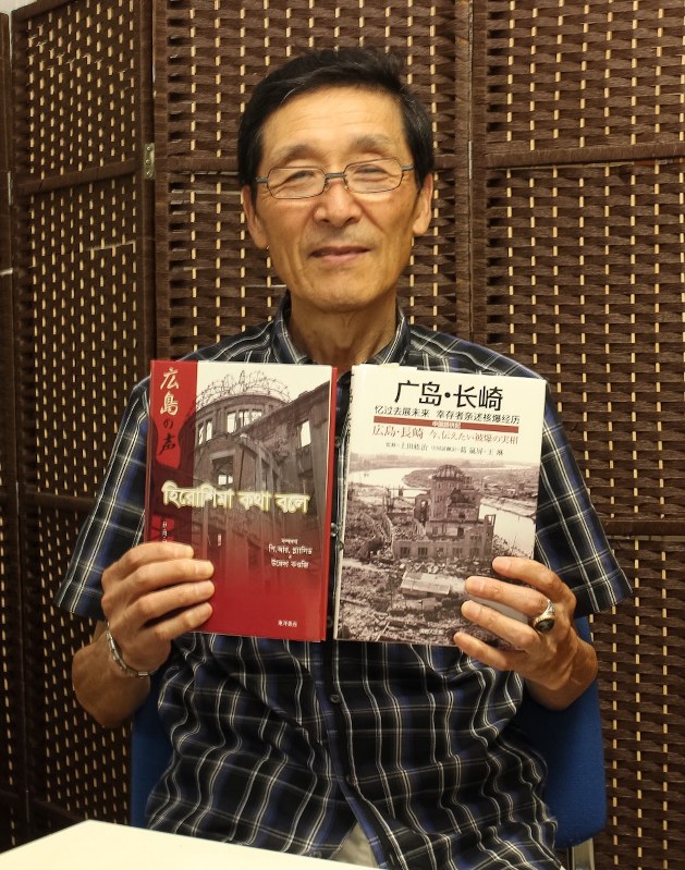 中国語版とベンガル語版の対訳本を手にする上田さん=八王子市内で