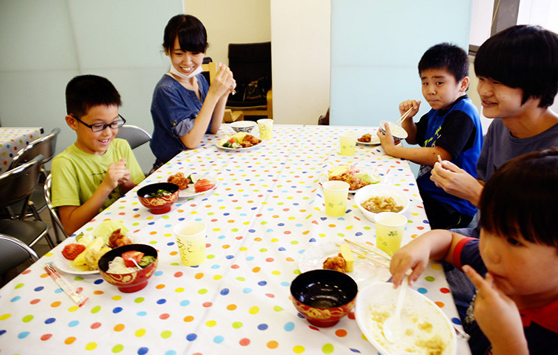 「みんなのごはん」で笑顔で食事をする子供や学生ボランティアら=神戸市北区で、神足俊輔撮影