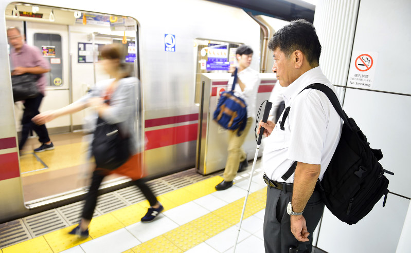 ほかの乗客との接触を避けるため、壁際に寄って電車を待つ藤井さん。転落事故以降、手助けをしてくれる人が増えたという=東京都中央区で、喜屋武真之介撮影