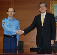 警視庁の高橋清孝・前警視総監（右）と事務引き継ぎをし、握手する沖田芳樹・新警視総監＝千代田区の警視庁本部で