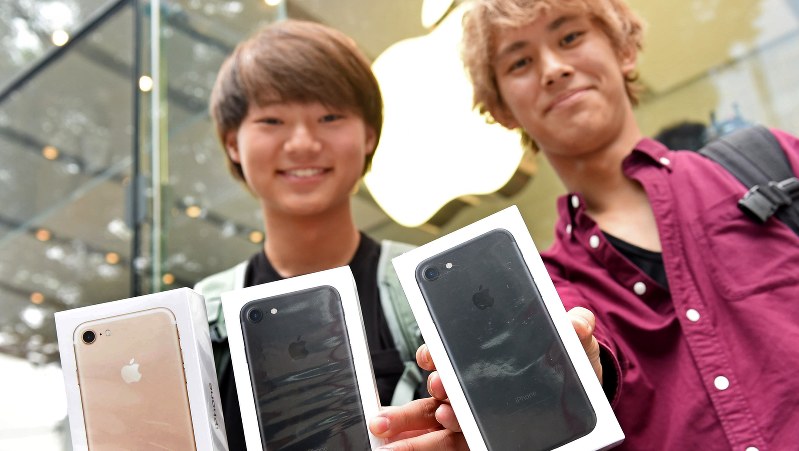 購入したiPhone 7や7 Plusを手に笑顔を見せる大学生=東京都渋谷区のアップルストア表参道店で、竹内紀臣撮影