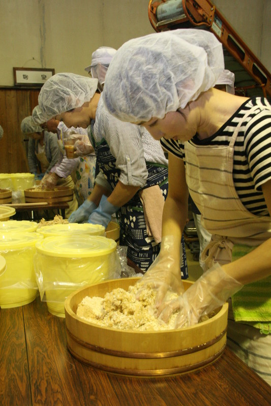 みそを仕込むため、大豆に、こうじと塩をしっかりと混ぜ合わせる参加者=須坂市新町で