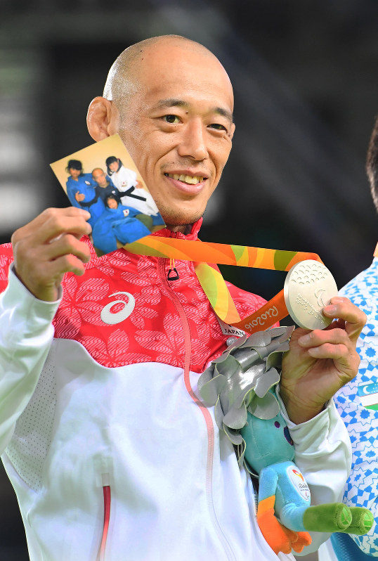 リオパラリンピック柔道男子60キロ級の表彰式で、家族の写真と銀メダルを一緒に掲げ笑顔を見せる広瀬誠さん=リオデジャネイロのカリオカアリーナで、徳野仁子撮影