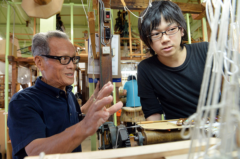 若手職人にアドバイスする岩間利夫さん(左)=京都市上京区の龍村美術織物烏丸工場で、小松雄介撮影