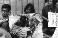 厚生省前で座り込み、水俣病患者の写真を掲げて企業責任を追及する「水俣病を告発する会」のメンバーら。中央が「苦海浄土」の著書・石牟礼道子さん＝１９７０年５月２５日撮影