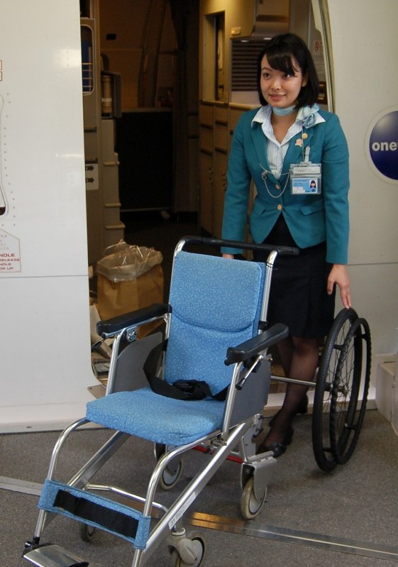 狭い機内に入るため、車いすの大きな車輪を取り外した空港コンシェルジュの染井彩美さん=2016年9月16日、西尾英之撮影