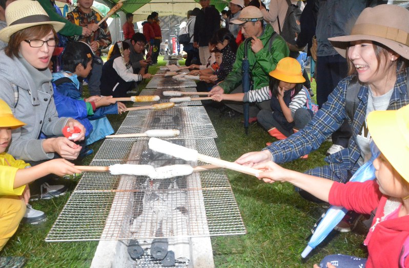 きりたんぽ1万本焼きを楽しむ家族連れ=秋田県大館市で2016年10月8日、田村彦志撮影