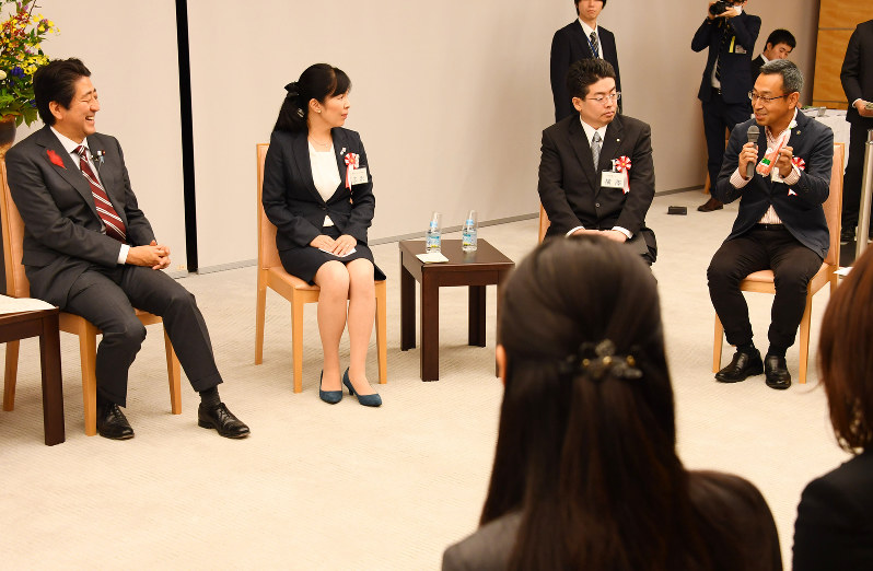 働き方改革に関する意見交換会で、栽培したニンジンを手にした出席者(右端)の話を聞く安倍晋三首相(左端)=首相官邸で2016年10月13日午後6時42分、川田雅浩撮影