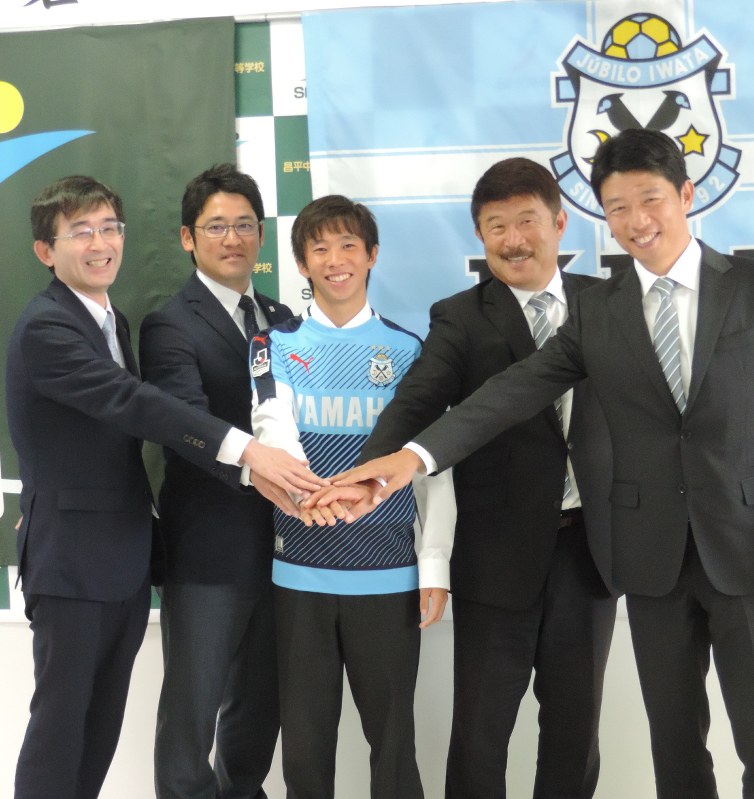 針谷岳晃選手(中央)と手を重ねる(左から)城川雅士校長、藤島崇之監督、加藤久・ジェビロ磐田ゼネラルマネジャー、服部年宏・同強化部長=杉戸町の昌平高で