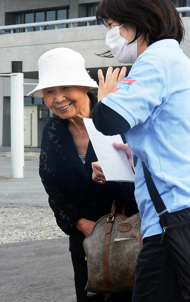 避難所の職員に付き添われて避難所を後にする藤田光子さん(左)=熊本県益城町の町総合体育館で、柿崎誠撮影