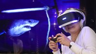 プレイステーションＶＲを体験する女性。左はヘッドセット内で見えている映像を映すモニター＝２０１６年１０月１３日、丸山博撮影