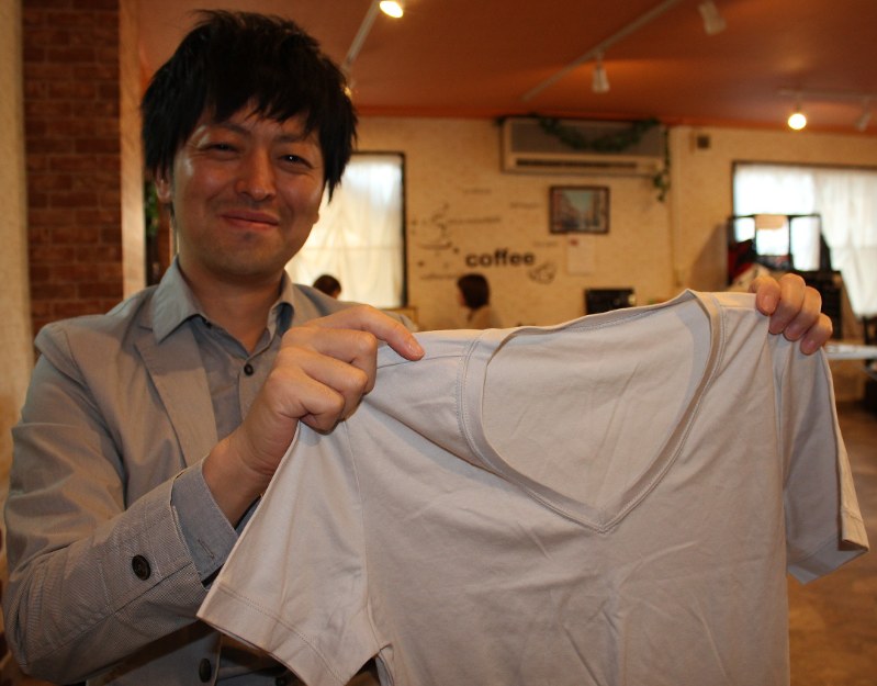 久慈市の工場で作られたTシャツを手にする香取正博さん=同市で