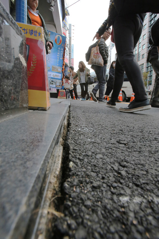 沈下によってできたとみられるビルの土台付近と歩道との隙間=福岡市博多区で2016年11月26日午前10時31分、和田大典撮影
