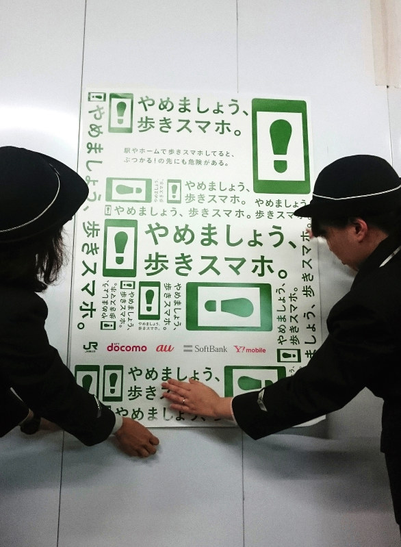 「歩きスマホ」を控えるよう呼びかけるポスターを掲示するJR社員=JR新宿駅新南口で、本多健撮影