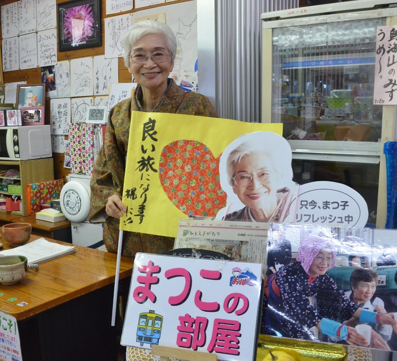 ホームで掲げる旗を手にする佐藤まつ子さん=由利本荘市の矢島駅で
