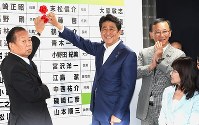 昨年の参院選で、満面の笑みで当選者の名前にバラを付ける安倍晋三首相（中央）。今年は悲願の憲法改正を目指し、衆院の解散・総選挙に打って出るのか＝東京都千代田区で２０１６年７月１０日、藤井太郎撮影