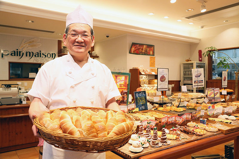 焼き上がったばかりの塩パンを手にする平田已登志さん=愛媛県八幡浜市北浜1で、山崎太郎撮影