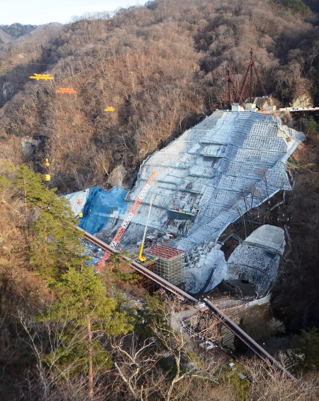 吾妻川の両岸で進む八ッ場ダム本体工事。来年中にも高さ116メートルの堤体が姿を現す。ここから上流にある川原湯温泉は高所に移転した=長野原町で
