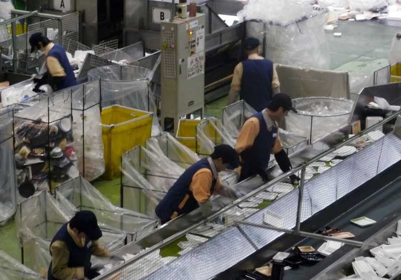 ラインに流れてくる回収トレーから不要品を取り除く障害者ら=茨城県八千代町のエフピコ関東リサイクル工場で